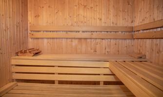 A cozy sauna with wooden paneling and bench cushions. The room is warm and inviting.