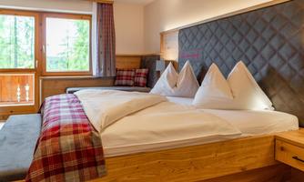 An inviting bedroom with a large bed and cozy decor. The windows offer a view of nature.
