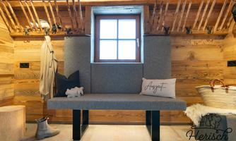 A cozy interior with wood panels and a window. A bench with cushions and a rustic ambiance.