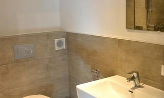 A modern bathroom with a white toilet and a sink. The walls are in neutral colors and there is a mirror above the sink.