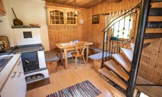 A cozy cabin with wood paneling and a dining area. A spiral staircase leads to an upper floor.