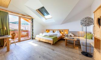 A cozy bedroom with a double bed and a seating area.  
Plenty of daylight streams through the large windows, giving the room an inviting atmosphere.