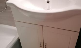 A bathroom with a modern sink and a white base cabinet. The room is bright and clean, with a carpet on the floor.