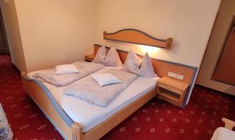 A cozy room with a double bed and a warm decor. The carpet and wooden design create an inviting atmosphere.