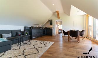 A modern apartment with wooden floors and bright walls. The room is well-furnished with a cozy couch and a dining table.