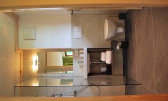 A modern bathroom with a glass shower and a simple sink. Towels and toiletries are neatly arranged.