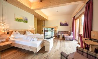 A modern room with wooden decor, a comfortable bed, and a television.  
Large windows provide plenty of daylight and a view of the surroundings.