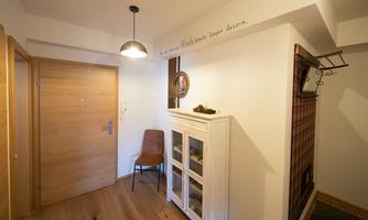 An inviting hallway with a wooden floor and a warm ceiling lamp. A decorative mirror hangs on the wall next to a stylish dresser.