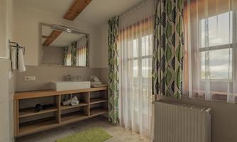A bright bathroom with a large mirror and stylish curtains. There is a sink area and a cozy atmosphere.
