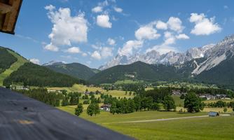 An impressive mountain landscape with green meadows and high mountains. The sky is beautifully blue with a few clouds.