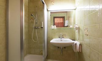 A modern bathroom with a shower and a sink. The walls are decorated in a cheerful green tone.
