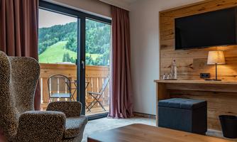 A cozy room with a beautiful view of the mountains. The room is modernly furnished with a TV and a sofa.
