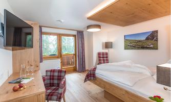 A modern bedroom with wooden furniture and a view of nature. The decor is cozy and inviting.