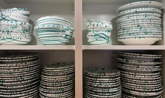 A shelf with various plates and bowls. The dishware has a blue-and-white pattern and is neatly stacked.