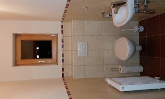A small, modern bathroom with a toilet and a sink. A window provides natural light.