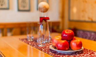 A table with a decorative arrangement of apples on a plate. In the background, there are glass containers and a sculpture.