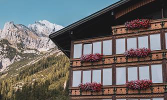 A traditional building with flower balconies. In the background, impressive mountains can be seen.