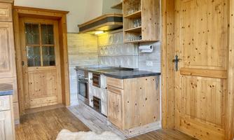 A cozy kitchen with wooden shelves and a modern stove. The atmosphere is warm and inviting.