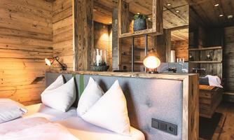 A cozy bedroom with wood paneling and modern furnishings. The beds are adorned with white pillows and the lighting creates an inviting atmosphere.