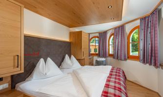 A cozy bedroom with a double bed and traditional pillows. Large windows let in plenty of light and create an inviting atmosphere.