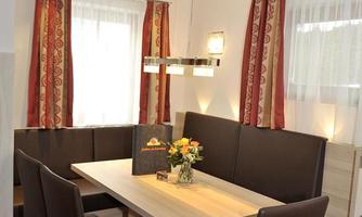 An inviting dining area with a modern table and elegant chairs. Curtains and comfortable lighting create a cozy atmosphere.