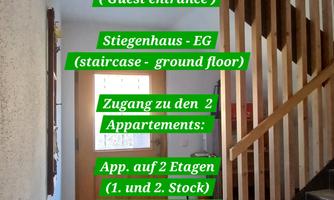 A foyer with a staircase and directional signs. The signs indicate the accesses to the apartments on different floors.