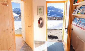 An inviting entrance with a view of snow-covered mountains. On the right side, there are bookshelves with magazines.