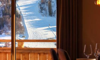 Insight into a winter landscape with snowy slopes. In the foreground, there are tables and chairs that create a cozy atmosphere.