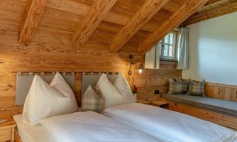 A cozy bedroom with a wooden ceiling and two single beds. The atmosphere is warm and inviting, perfect for relaxation.