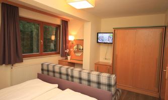 A cozy room with a double bed and a television. Large windows let in plenty of light and offer a view outside.