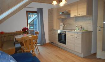 A cozy kitchen with wooden cabinets and a dining table. The room has plenty of natural light and a modern style.