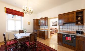 A stylish kitchen with a wooden dining table and elegant chairs. The warm colors and the carpet give the room an inviting atmosphere.