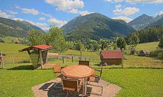 A beautiful view of the mountains and the green valley. At the table in the foreground, one can enjoy nature.