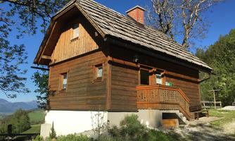 A charming wooden house with a steep roof and a porch. Surrounded by trees and beautiful scenery.