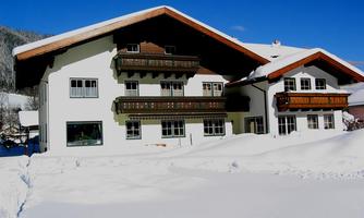 A charming alpine-style building surrounded by snow. The clear blue sky creates a lovely winter atmosphere.