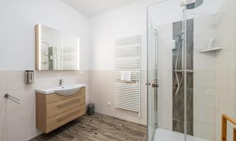 A modern bathroom with an unheated shower and a wooden sink. Bright tiles and an elegant mirror create a friendly atmosphere.