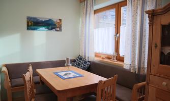 A cozy dining area with a wooden table and benches. The window lets in plenty of light and offers a picturesque view.