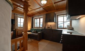 A cozy living space with wooden elements and large windows. The modern kitchen and the comfortable seating area invite you to relax.