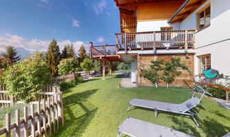 A beautiful property with a garden and sun umbrellas. In the background, you can see a wooden house and a clear sky.