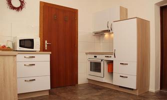 A modern kitchen with white cabinets and a wood stove. On the wall, a refrigerator and a microwave are visible.