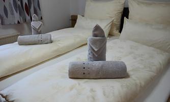 A cozy bedroom with two beds and comfortable bedding. Towels are neatly folded and decoratively placed on the beds.