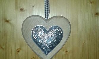 A wooden hanging heart with a metallic heart in the middle. It has a checked ribbon for hanging.