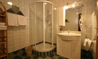 A modern bathroom with a shower cubicle and a washbasin. White tiles and a colorful floor create a pleasant atmosphere.