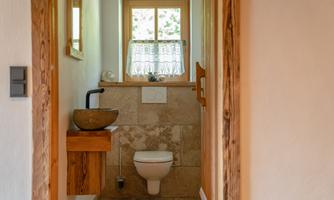 A modern bathroom with a wooden table and an elegant sink. The window lets in plenty of light and creates a friendly atmosphere.