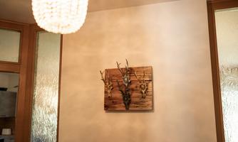 A rustic wall painting with antlers on a wooden background. In the background, a stylish ceiling light can be seen.