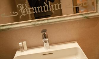 A modern sink with an elegant faucet. The writing "Brandhor" is visible in the mirror.