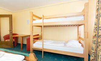 A simple room with a bunk bed and a table. The walls are yellow and there is a carpeted floor.