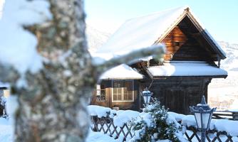 A pretty wooden house in the snow, surrounded by snow-covered trees. The clear winter landscape radiates tranquility and coziness.