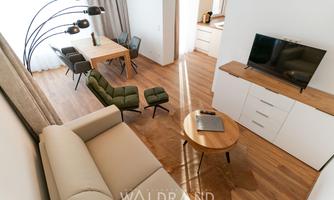 A modern apartment with a bright living room. Furniture such as a sofa, a dining table, and a television create an inviting atmosphere.