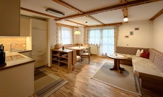 A cozy apartment with an open kitchen and dining area. Bright windows and wood details create an inviting atmosphere.